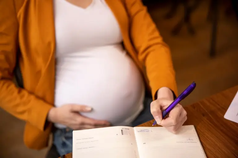 Licença maternidade: gestante cariciando a própria barriga enquanto assina documento