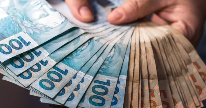 Pessoa oferecendo notas de dinheiro, fazendo alusão ao abono pecuniário