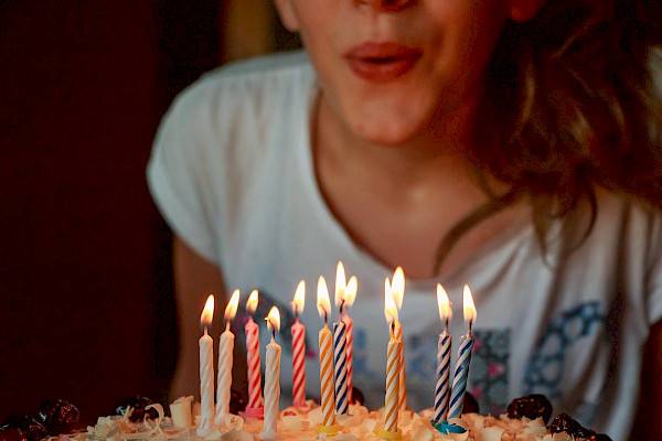 mulher assoprando velas de um bolo de aniversário como alusão ao day off de aniversário