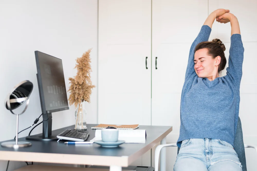 ginástica laboral: colaboradora vestindo uma blusa azul se espreguiçando em frente ao computador