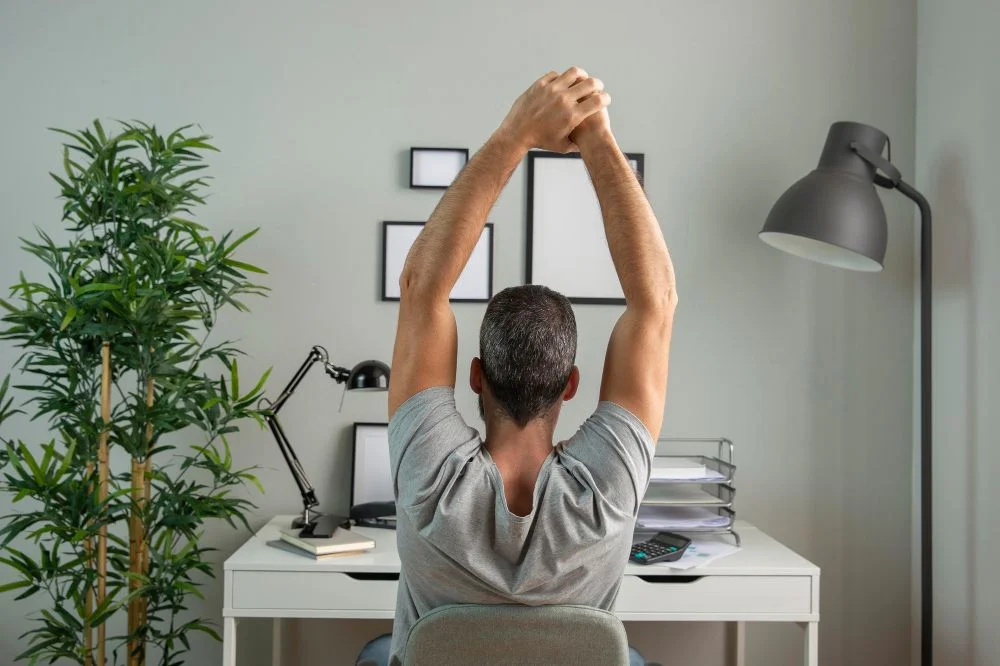 ergonomia no trabalho: homem branco se espreguiçando durante o expediente