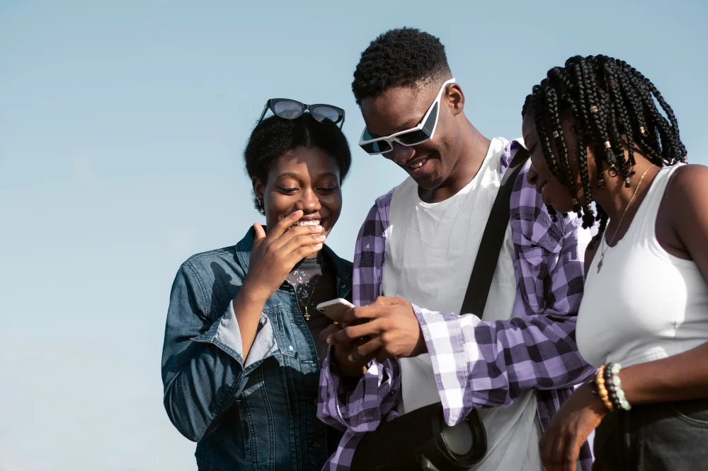 Geração Z: três jovens negros reunidos enquanto usam o telefone