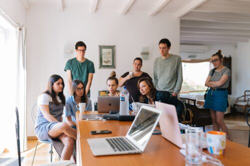 equipe de trabalho reunida em uma sala olhando para um computador