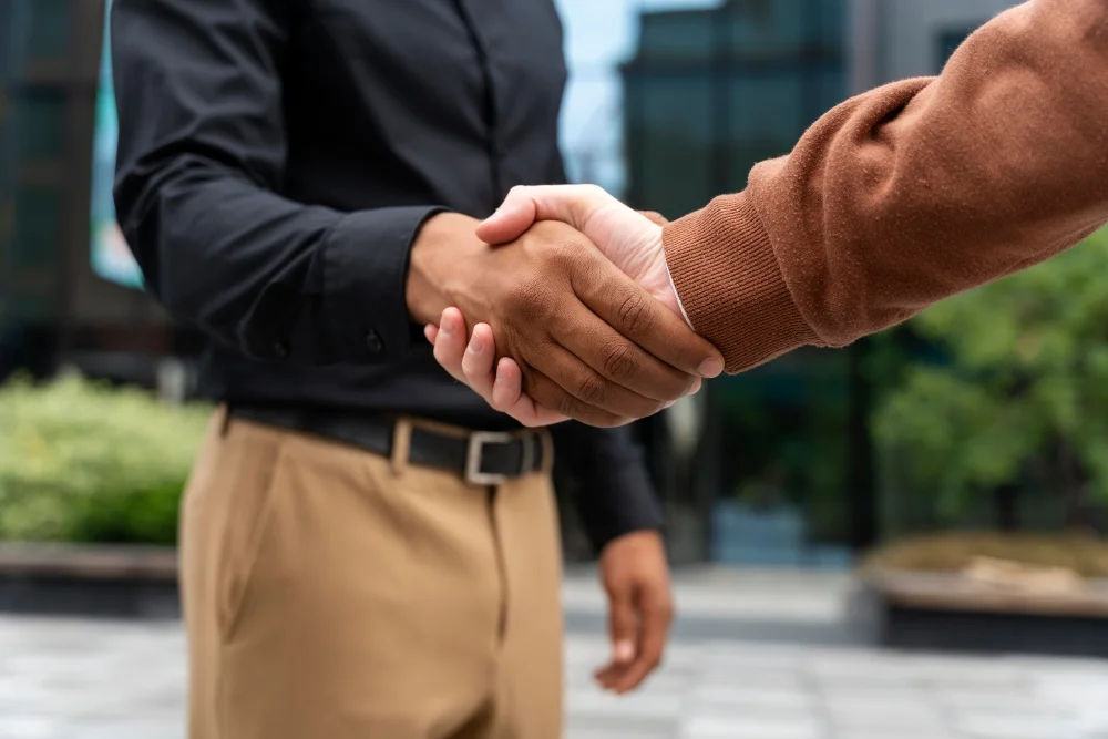 Benchmarking: dois homens colaboradores de empresas diferentes apertando as mãos