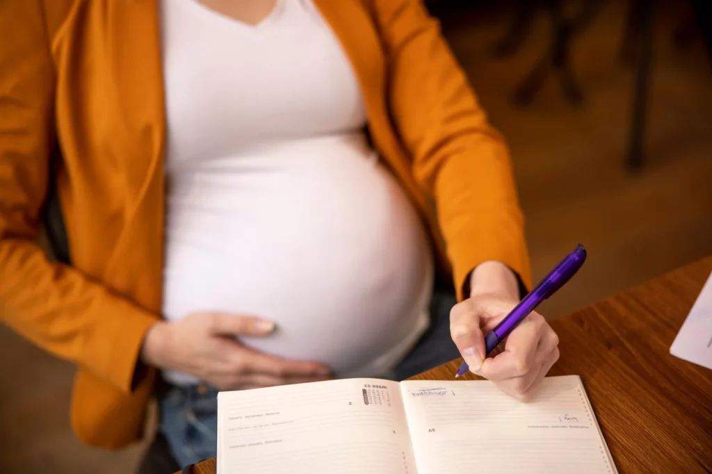 Licença maternidade: gestante cariciando a própria barriga enquanto assina documento